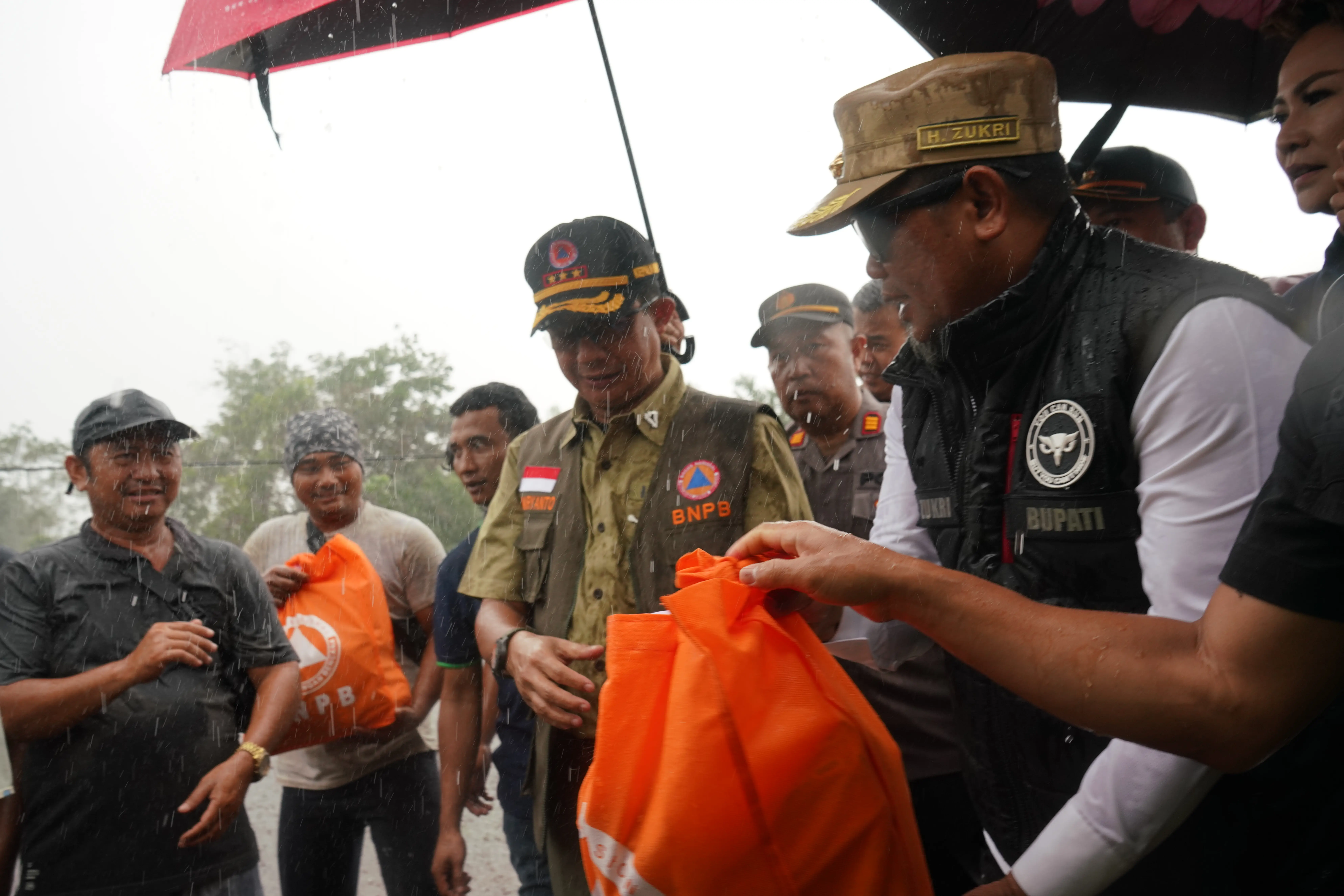 Kepala BNPB Letjen TNI Suharyanto, S.Sos., M.M menyerahkan bantuan kepada perwakilan warga terdampak banjir di Kabupaten Pelalawan, Provinsi Riau, Kamis (18/1). 